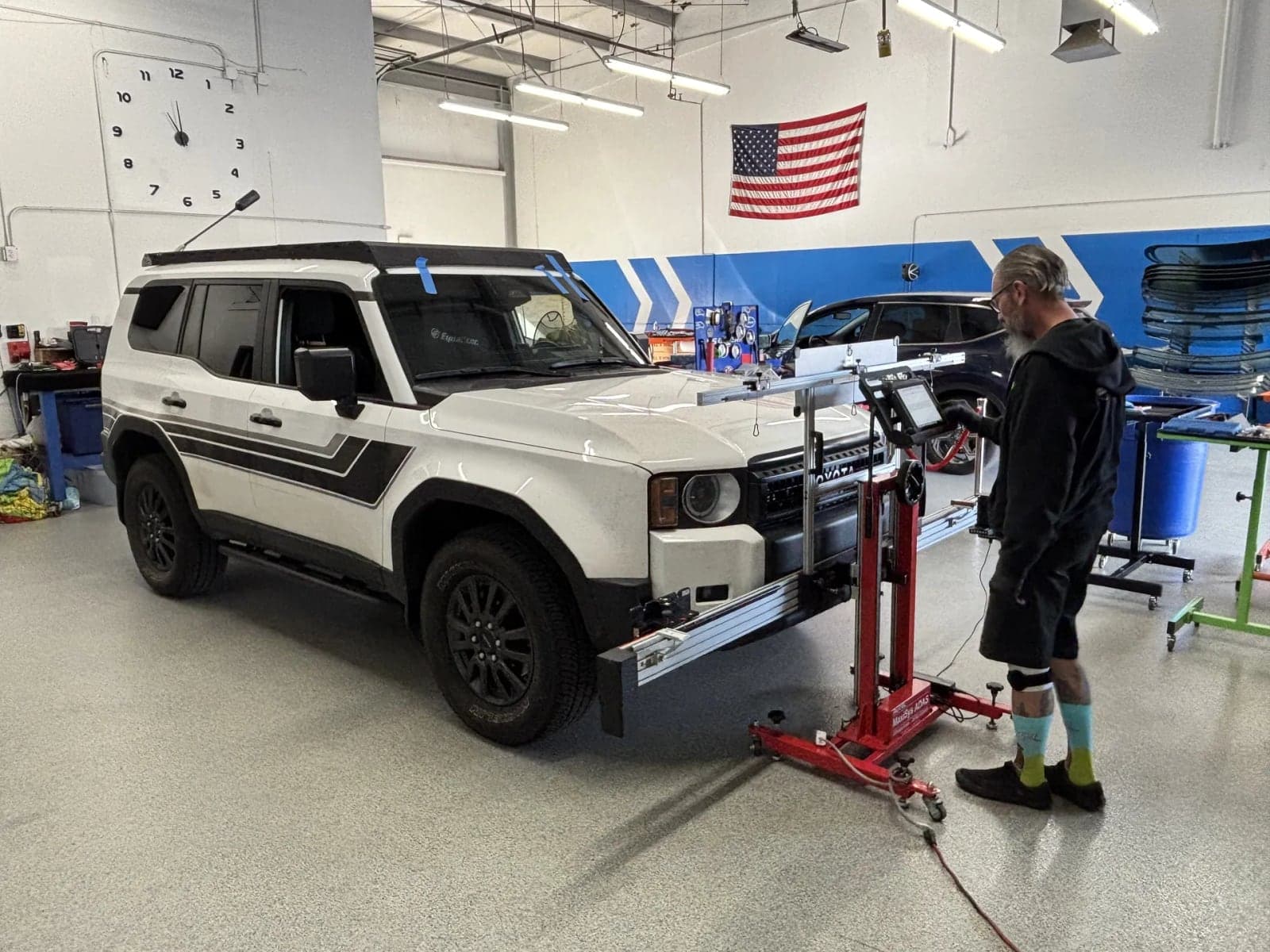 Technician running ADAS camera calibration on a white SUV